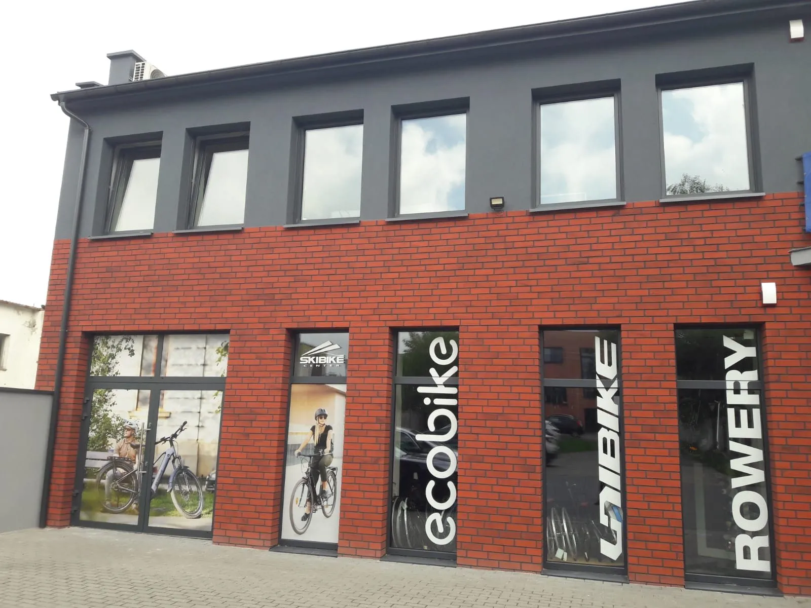 Budynek salonu Skibike Center od frontu — parter z czerwonej cegły, witryny z napisami Ecobike, Unibike i Rowery